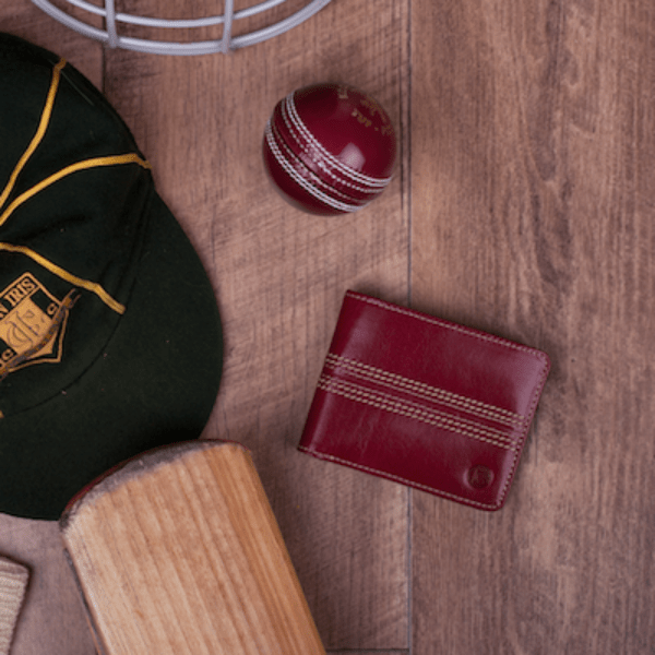 cherry leather cricket wallet on table with bat and ball